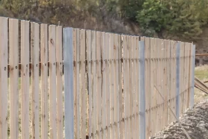 Wooden picket fence boards being installed, illustrating options for backyard fencing.